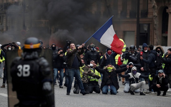 A protester waves a French flag during clashes with police at a demonstration by the "yellow vests" movement in Paris